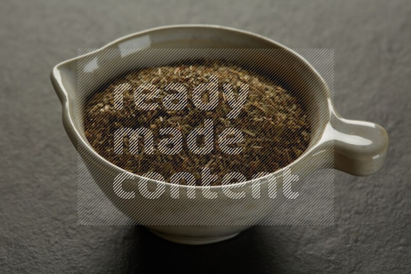 multi color round sauce bowl filled with herbs on grey textured countertop