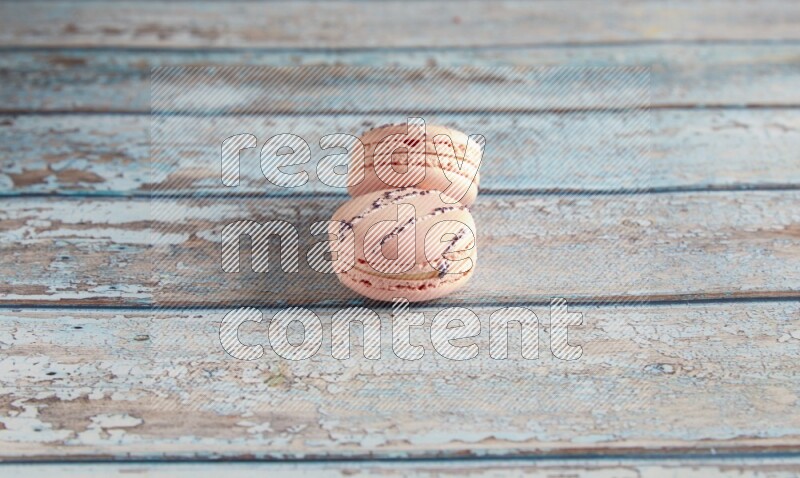 45º Shot of two pink orange blossom macarons on light blue wooden background