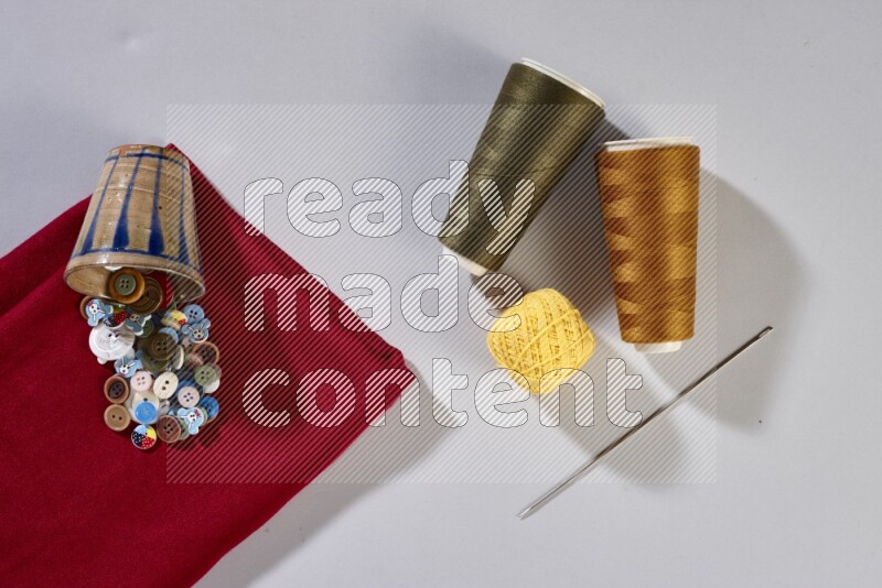 Multicolored fabrics with sewing supplies on grey background