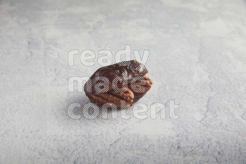 pecan stuffed madjoul date on a light grey background