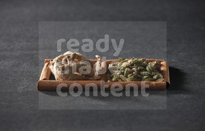 2 squares of cinnamon sticks full of cardamom and dried ginger on black flooring