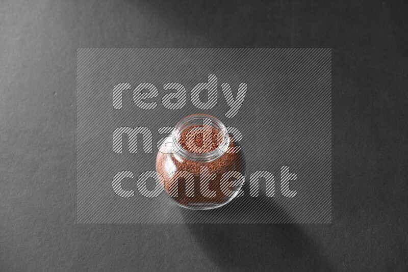 A glass spice jar full of garden cress on black flooring