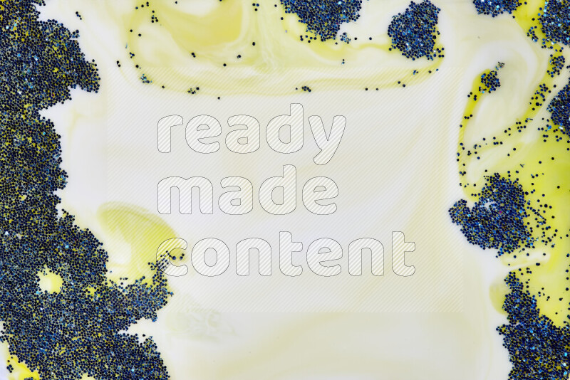 A close-up of sparkling blue glitter scattered on swirling yellow background