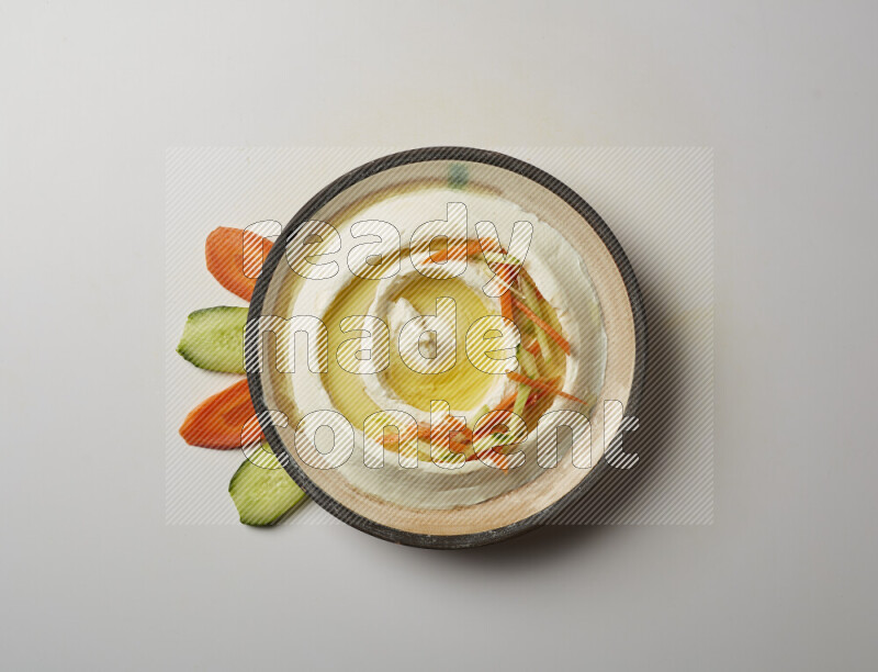Lebnah garnished with sliced carrots &cucumber in a pottery plate on a white background