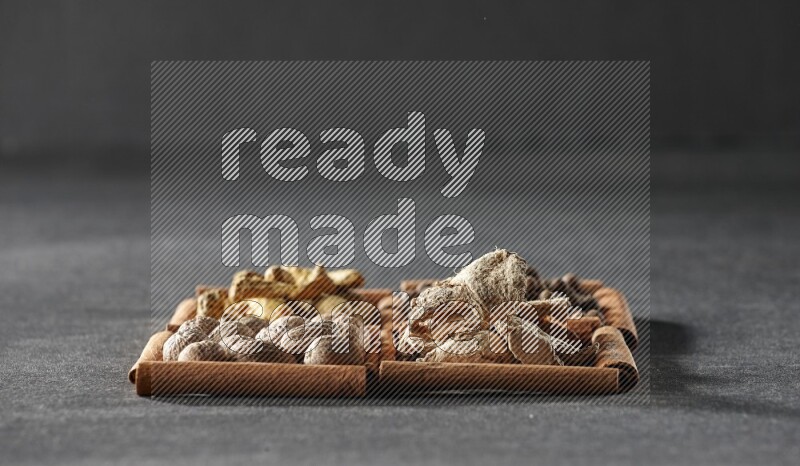 4 squares of cinnamon sticks full of turmeric fingers, allspice, dried ginger and nutmegs on black flooring