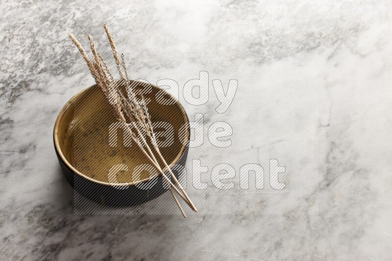 Wheat stalks on multicolored pottery oven plate on grey marble background