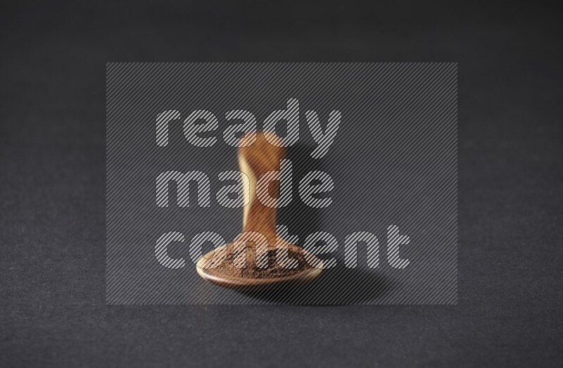 بودرة القرنفل في ملعقة خشبية علي خلفية سوداء