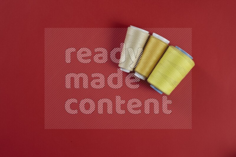 مجموعة من أدوات الخياطة والتفصيل صفراء اللون على خلفية حمراء