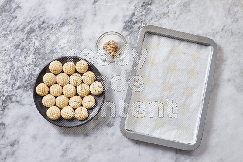 كحك خطوة بخطوة بمكوناته سمن، سكر، دقيق، سمسم، خميرة، ماء ونكهة الكحك على خلفية رخام رمادي