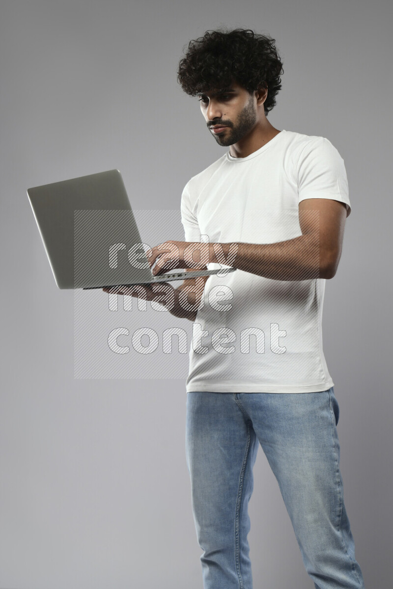 A man wearing casual standing and working on a laptop on white background