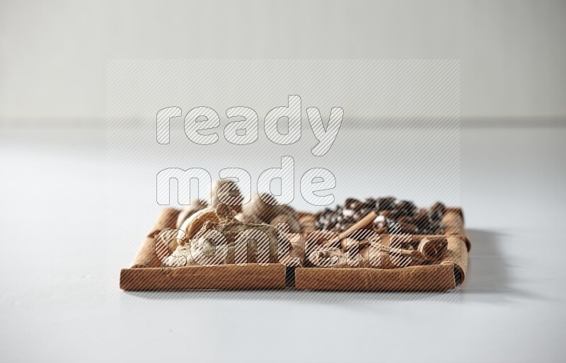 4 squares of cinnamon sticks full of coffee beans, nutmeg, cinnamon and dried ginger on white flooring