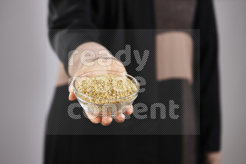 Woman in abaya holding different kinds of legumes in different positions