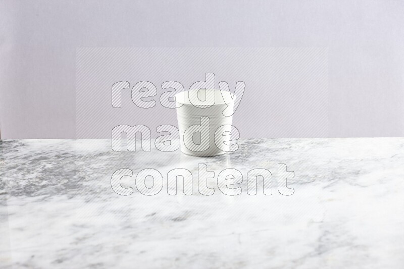 An empty white plant pot on grey marble background