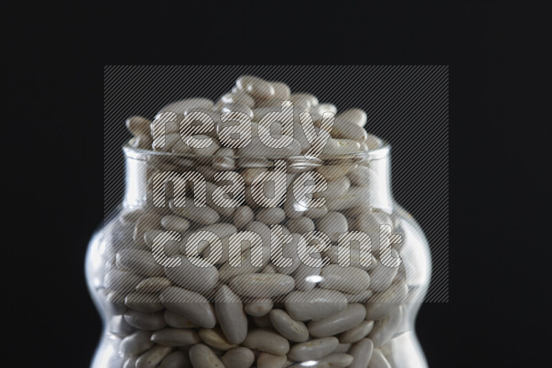 White beans in a glass jar on black background