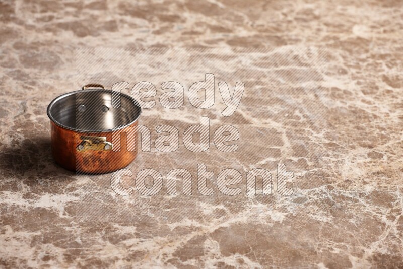 A small copper pot on beige marble background