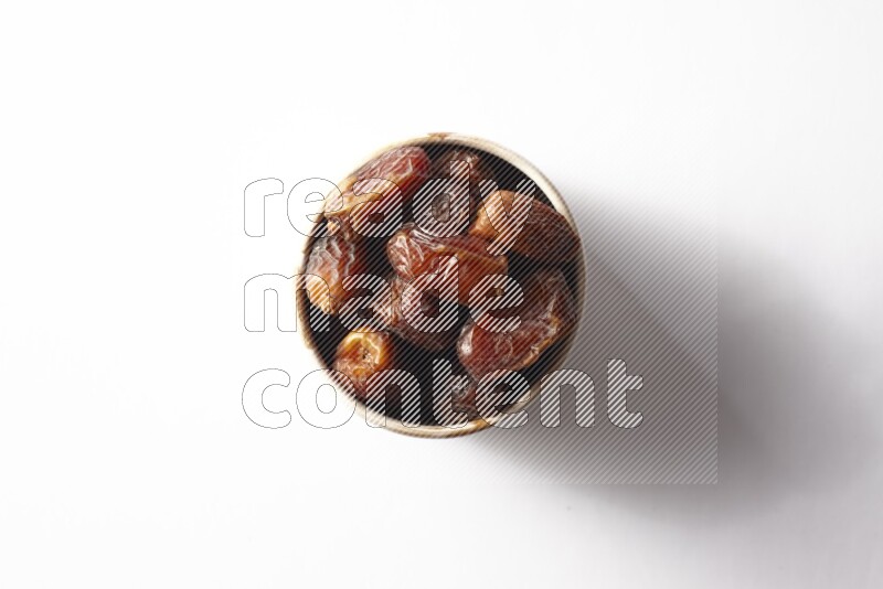 Dates in a beige pottery bowl on white background