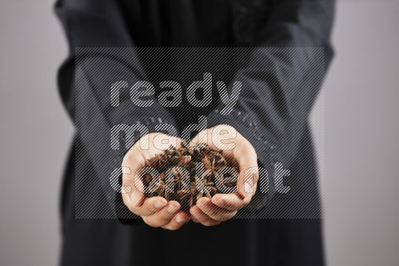 Woman in abaya holding different kinds of spices in different positions