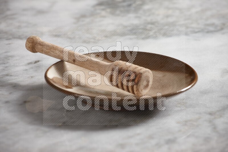 Multicolored pottery plate with wooden honey dipper in it on grey marble background