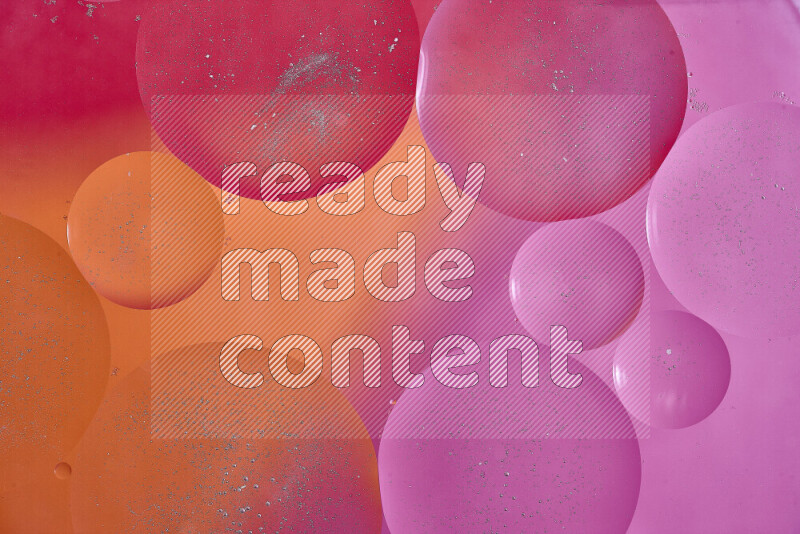 Close-ups of abstract oil bubbles on water surface in shades of red, orange and pink