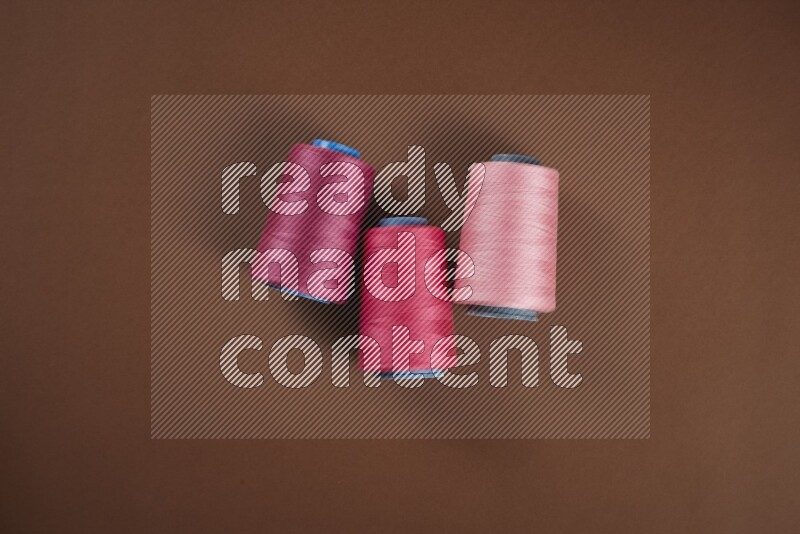 A pink collection of sewing and tailoring tools arranged on a brown background