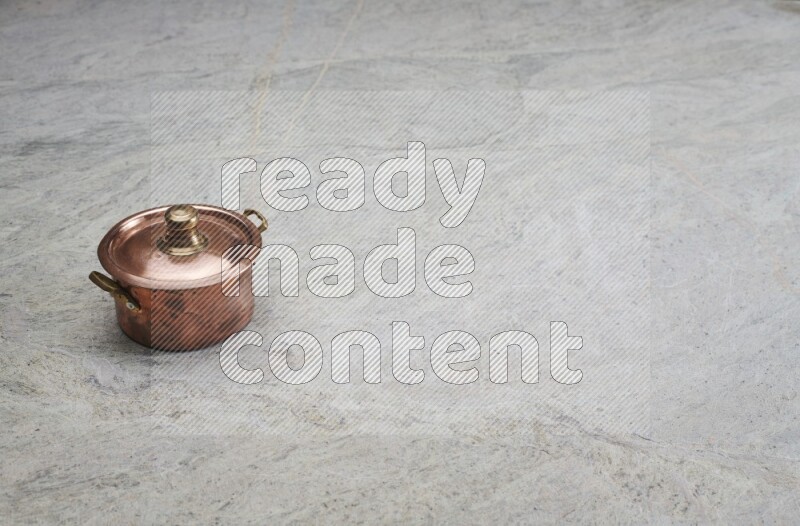 A small copper pot on grey marble background