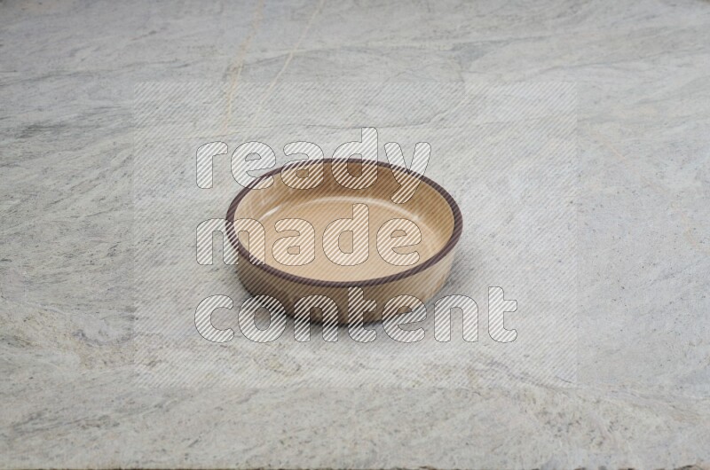 A beige pottery oven bowl on grey marble background