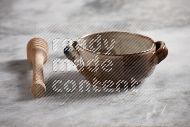 Multicolored pottery bowl with wooden honey dipper on the side on grey marble background