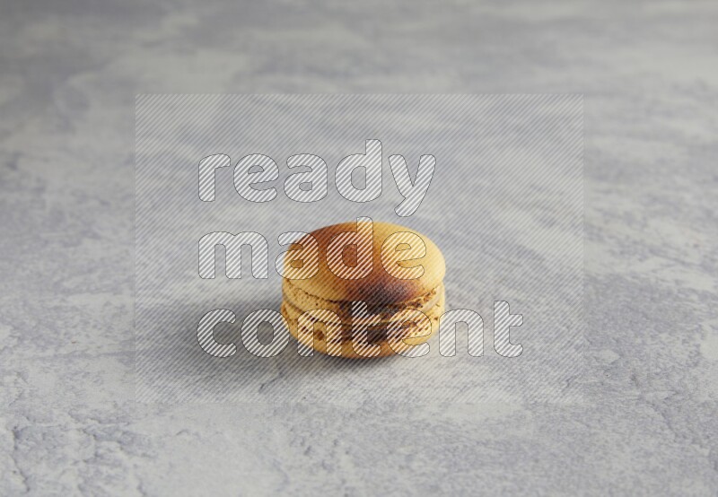 45º Shot of Yellow Crème Brulée macaron on white marble