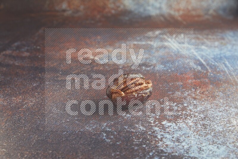 one pecan stuffed madjoul date on a rustic reddish background