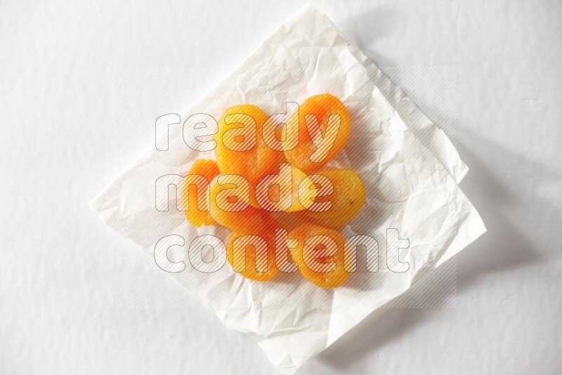 Dried apricots on a crumpled piece of paper on a white background in different angles
