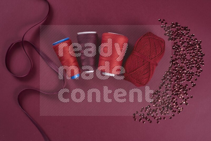 A red collection of sewing and tailoring tools arranged on a red background