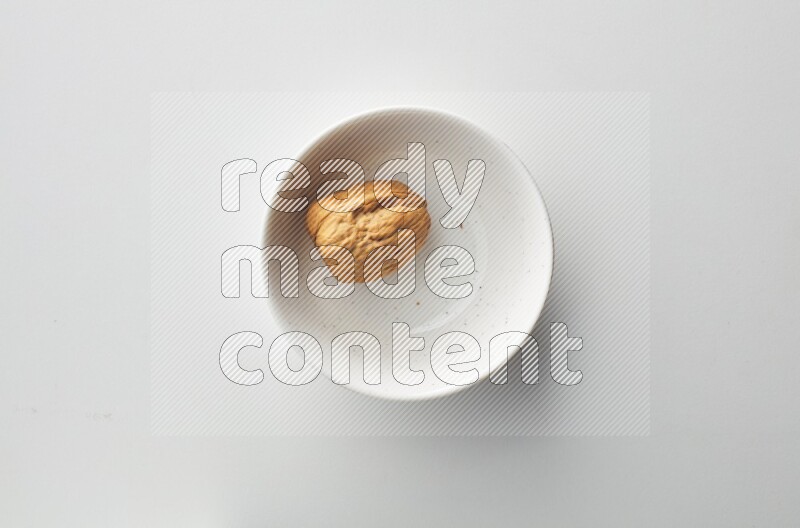 Top-view shot of walnut in a container on white background