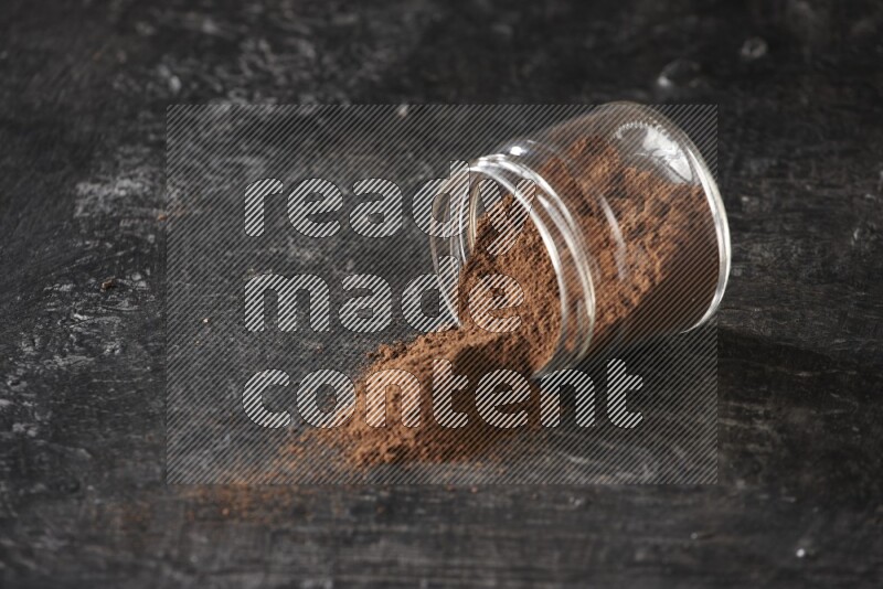 وعاء زجاجي مقلوب ممتلئ ببودرة القرنفل على أرضية سوداء