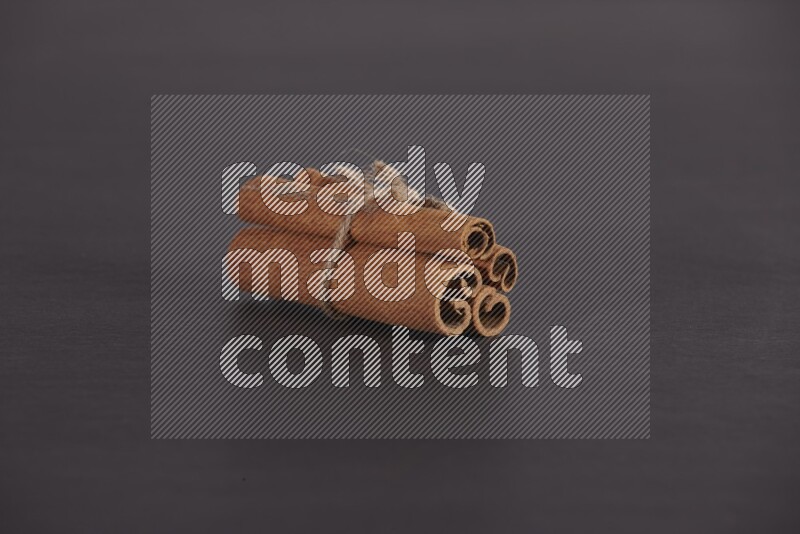 4 Cinnamon sticks stacked and bounded on black flooring