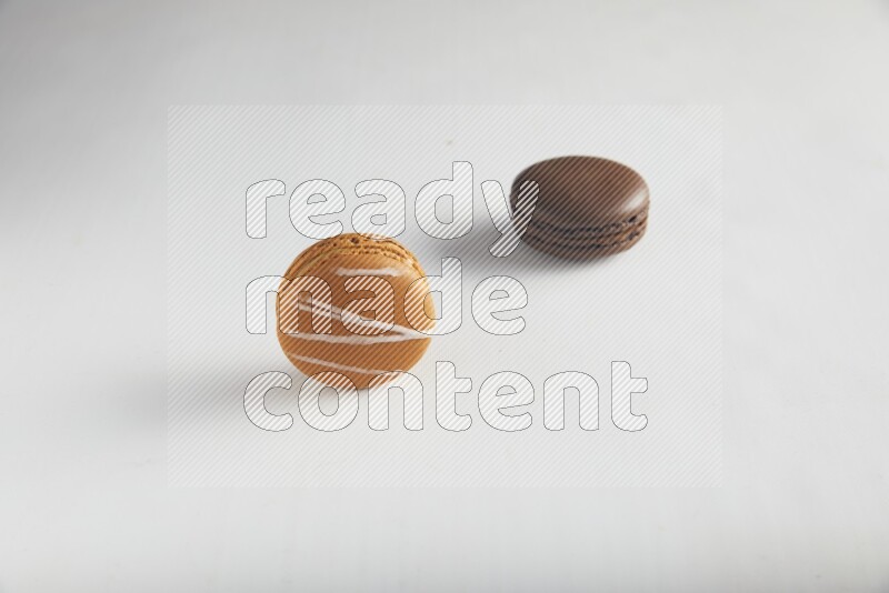 45º Shot of of two assorted Brown Irish Cream, and Brown Dark Chocolate macarons on white background
