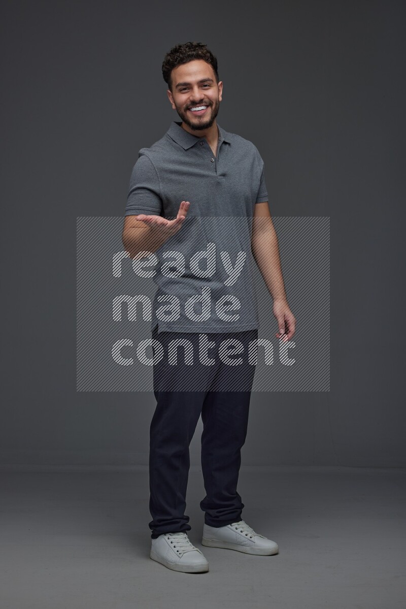 A man wearing casual standing and making multi hand gestures eye level on a gray background