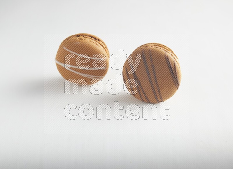 45º Shot of of two assorted Brown Irish Cream, and light brown  Almond Cream macarons on white background