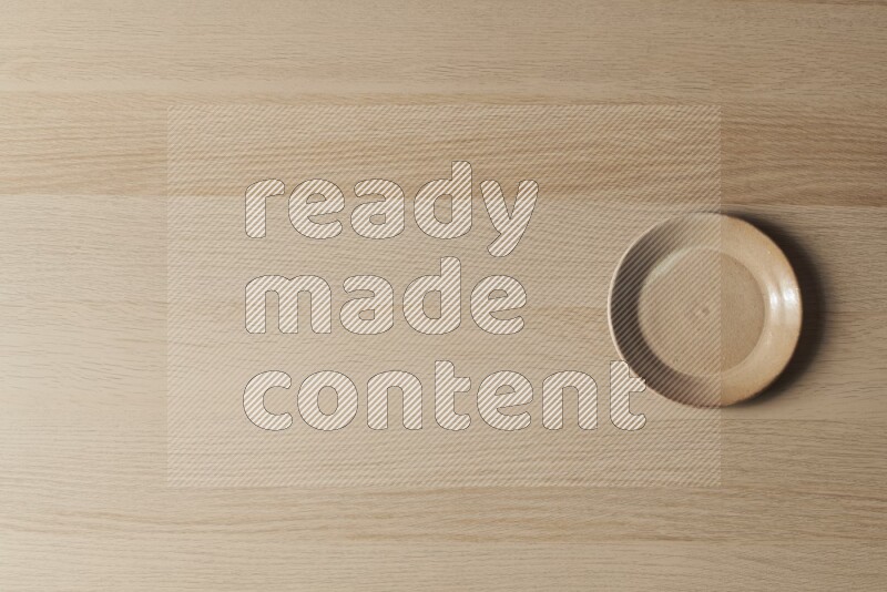 A beige pottery plate on light wooden background