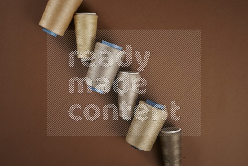 A brown collection of sewing and tailoring tools arranged on a brown background