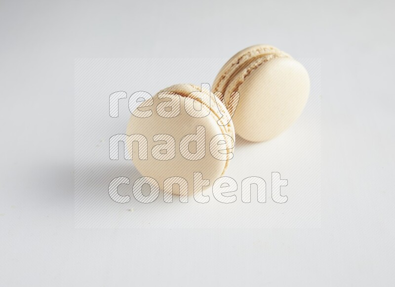 45º Shot of two White Caramel fleur de sel macarons on white background