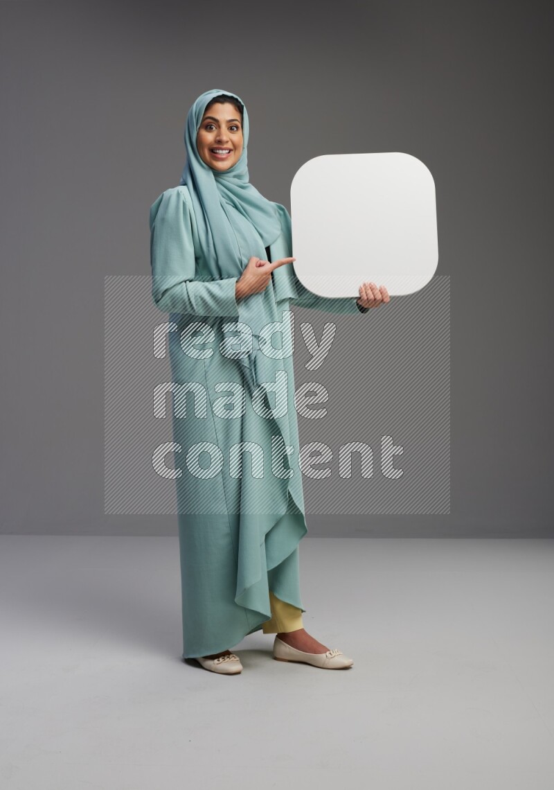 Saudi Woman wearing Abaya standing holding social media sign on Gray background