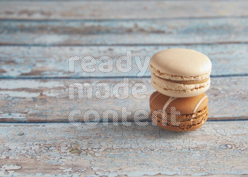 45º Shot of of two assorted Brown Irish Cream, and White Caramel fleur de sel macarons on light blue background