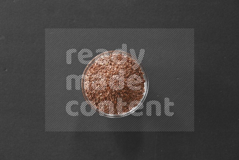 A glass bowl full of flax on black flooring