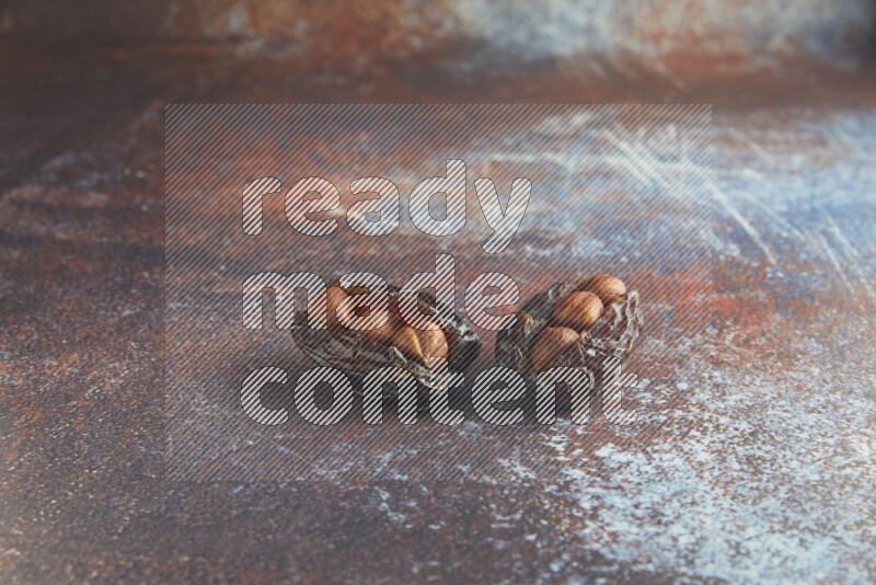 two hazelnut stuffed madjoul dates on a rustic reddish background