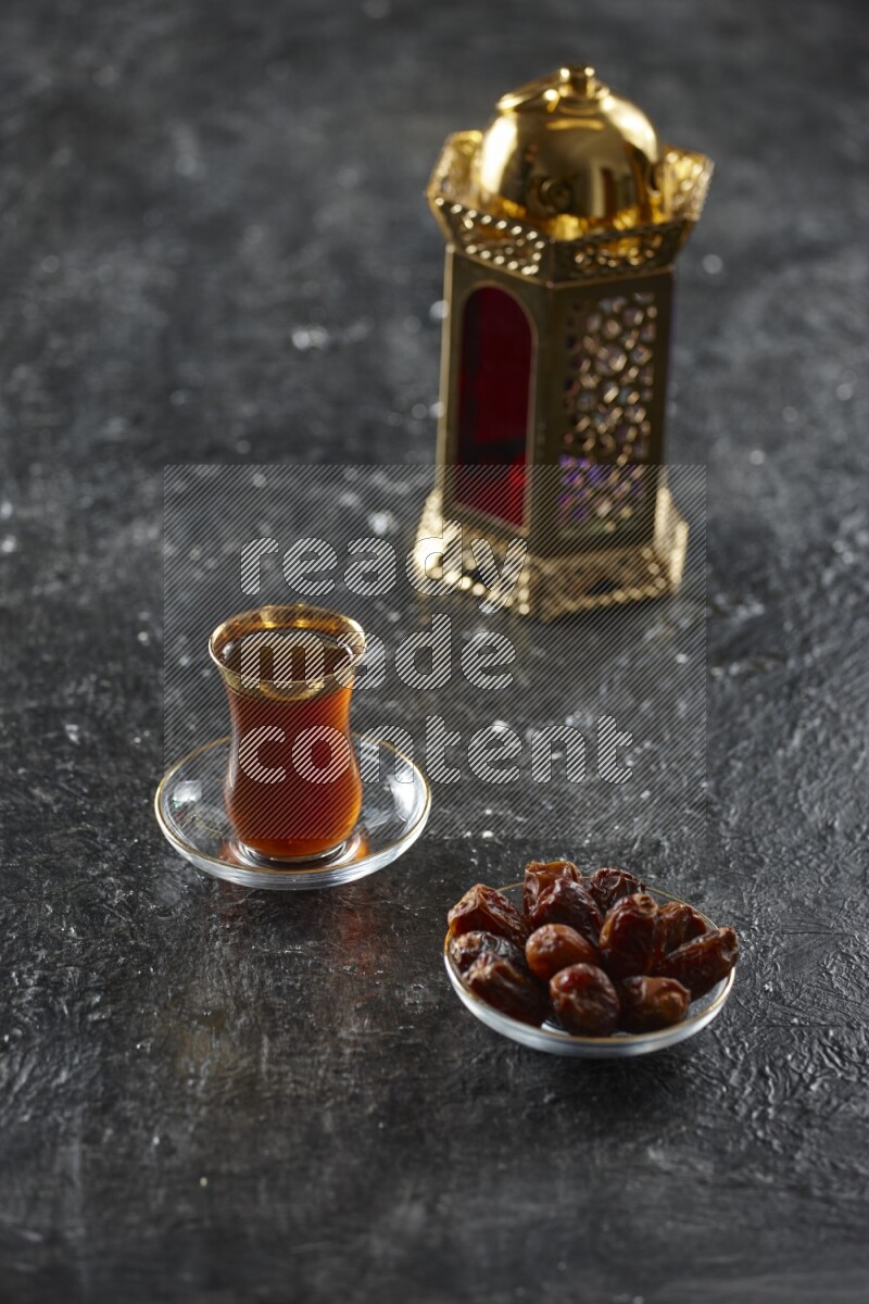 A golden lantern with different drinks, dates, nuts, prayer beads and quran on textured black background