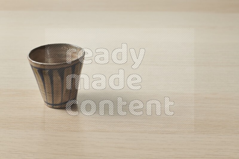 A pottery cup on light wooden background