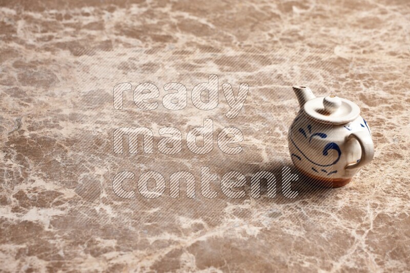 A pottery teapot on beige marble background