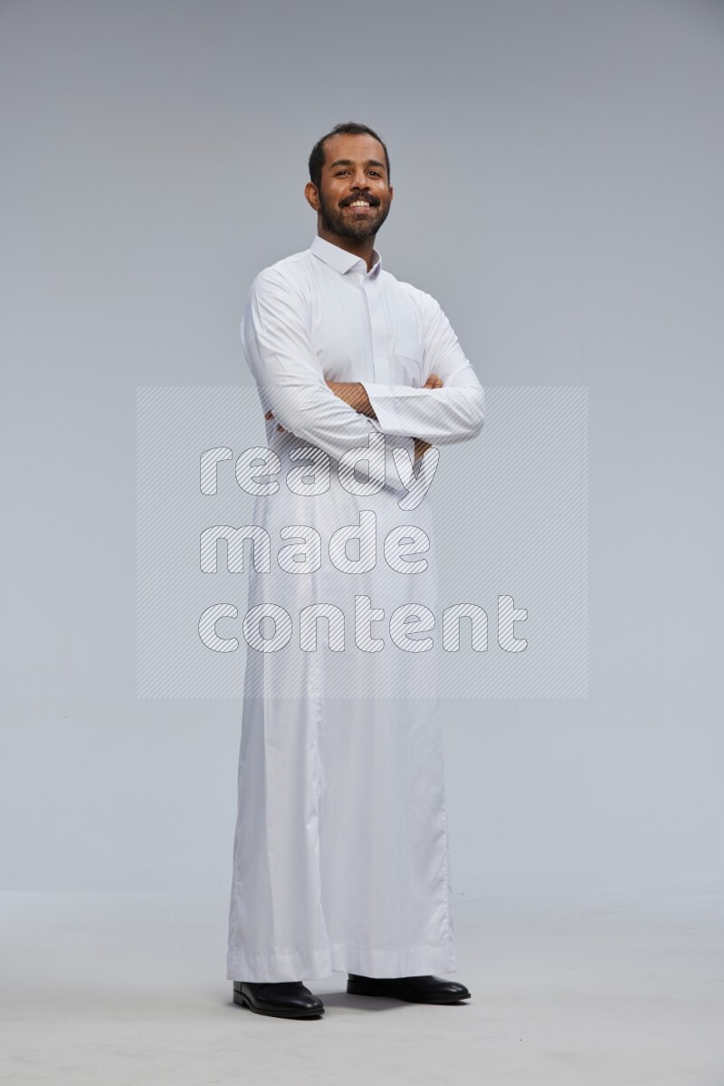 Saudi man wearing Thob standing with crossed arms on Gray background