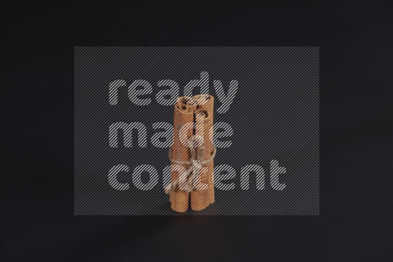 4 Cinnamon sticks stacked and bounded on black flooring
