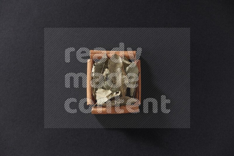 A single square of cinnamon sticks full of laurel bay on black flooring